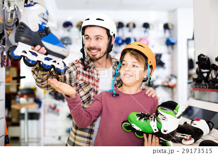 father and son deciding on new roller-skates in sports store father and son deciding on new roller-skates in sports store 29173515