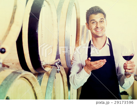 Seller pouring wine in cellar 29173596