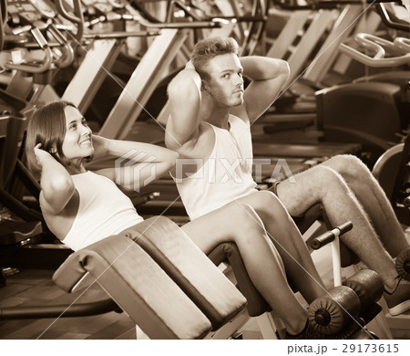 Well trained glad young man and woman training abdominal muscles in gym Well trained glad young man and woman training abdominal muscles in gym 29173615