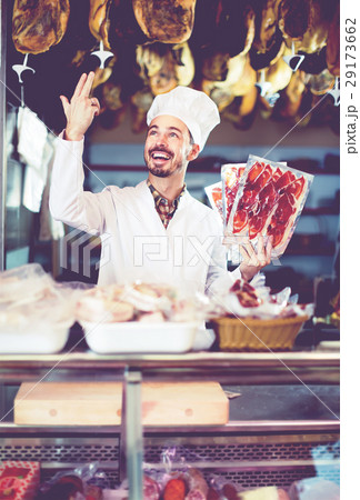 cheerful man seller showing sliced bacon in shop 29173662