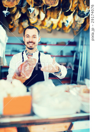 Male shop assistant demonstrating piece of meat in butcher’s shop 29174076