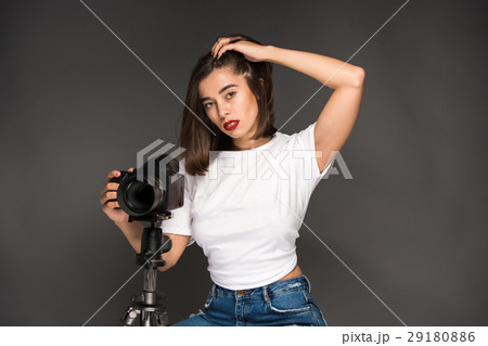 Portrait of a young woman with camera on the gray 29180886
