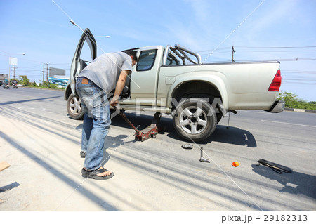 A man changing the wheel at the side of the road 29182313