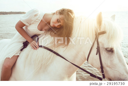 Girl in white dress with horse on the beach 29195730