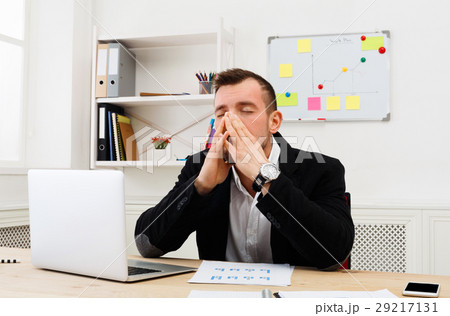 Young stressed businessman with laptop in modern Young stressed businessman with laptop in modern 29217131