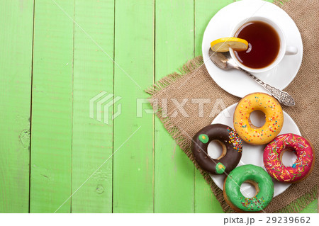 glazed donuts with a cup of tea on a green wooden glazed donuts with a cup of tea on a green wooden 29239662