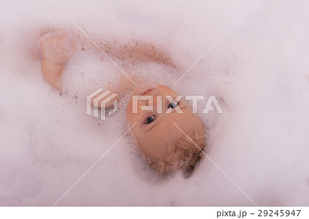 A baby in a bathtub in soap foam looking at camera A baby in a bathtub in soap foam looking at camera 29245947
