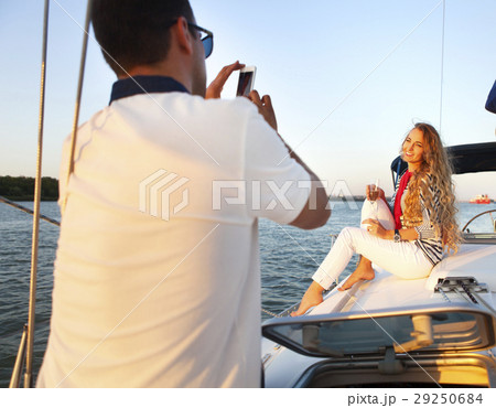 Beautiful couple taking a photo on a sailing boat Beautiful couple taking a photo on a sailing boat 29250684
