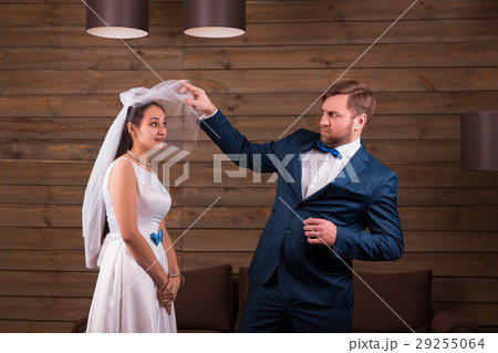 Bride in dress and veil against groom in suit Bride in dress and veil against groom in suit 29255064