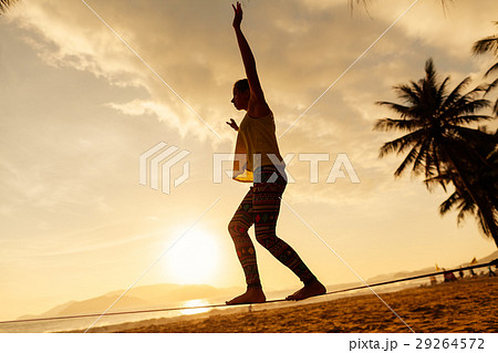 teenage girl  balancing on slackline silhouette on the beach 29264572