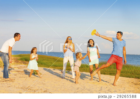Friends with children playing frisbee on the beach 29265588