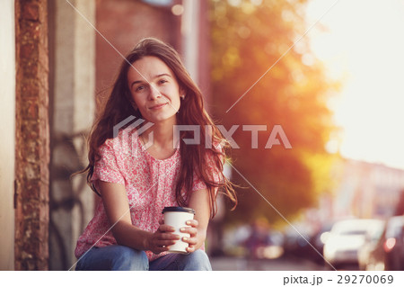 smiling pretty girl sitting in street with coffee 29270069