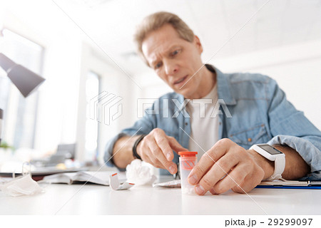 Attentive male person staring on box with pills Attentive male person staring on box with pills 29299097
