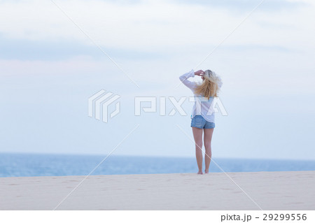 Woman on sandy beach in white shirt at dusk.  29299556