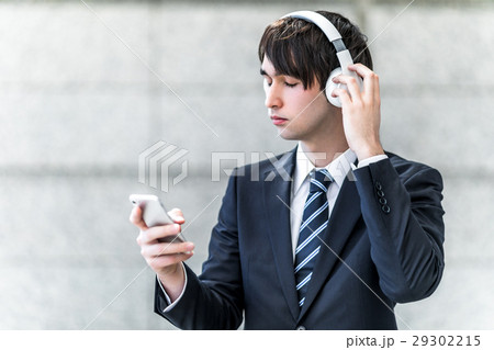 ワイヤレスヘッドホンとスマホで音楽を聴く男性 29302215