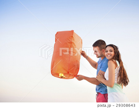 Young couple start a red Chinese sky lantern Young couple start a red Chinese sky lantern 29308643