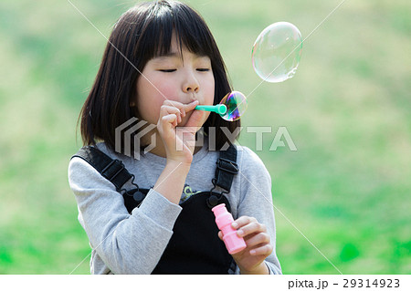 シャボン玉で遊ぶ小学生の女の子の写真素材