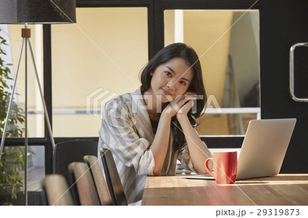 The woman is sitting by the laptop in the office The woman is sitting by the laptop in the office 29319873