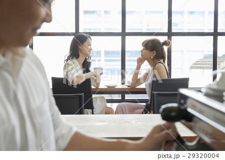 Two beautiful women holding cup of coffee and talking to each other. Two beautiful women holding cup of coffee and talking to each other. 29320004