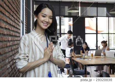 The beautiful woman smiling while colleagues discussing at the back. 29320030