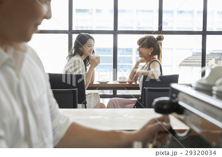 Portrait of two women talking and drinking coffee in café 29320034