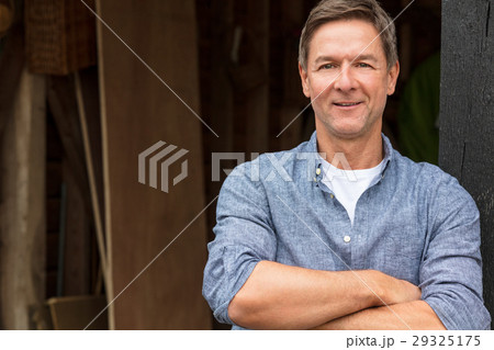Happy Middle Aged Man Arms Folded by His Garage Happy Middle Aged Man Arms Folded by His Garage 29325175