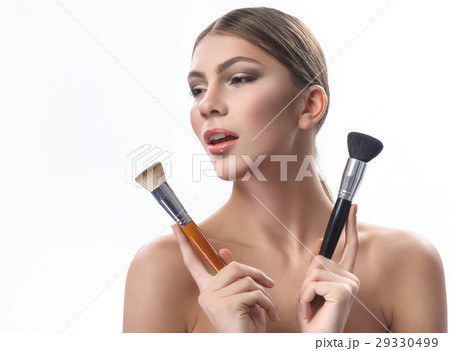 Gorgeous young woman holding makeup brushes 29330499
