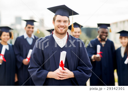 happy students in mortar boards with diplomas 29342301