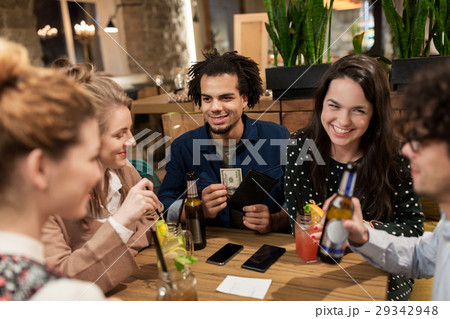 friends with drinks, money and bill at bar 29342948