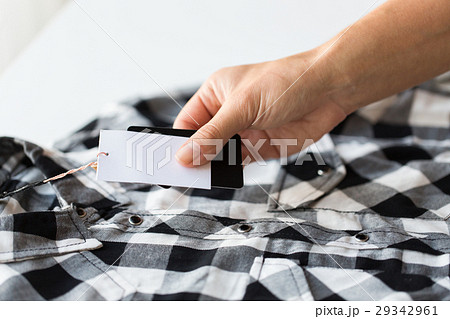 close up of hand holding checkered shirt price tag 29342961