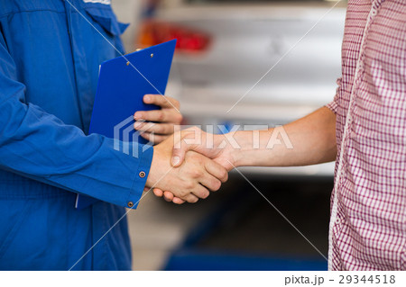 auto mechanic and man shaking hands at car shop 29344518