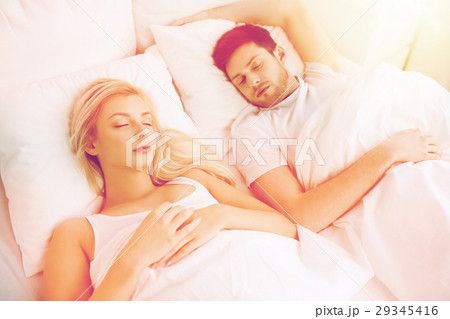 happy couple sleeping in bed at home 29345416