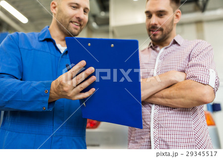 auto mechanic with clipboard and man at car shop auto mechanic with clipboard and man at car shop 29345517