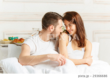 Young adult heterosexual couple lying on bed in 29366686