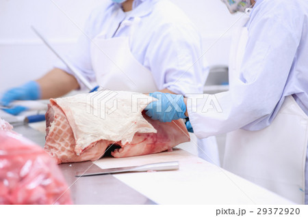 butcher cutting the skin of fresh pork 29372920