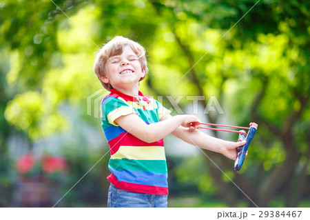 little kid boy shooting wooden slingshot little kid boy shooting wooden slingshot 29384467