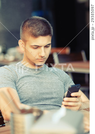 Man with mobile phone in restaurant 29385097