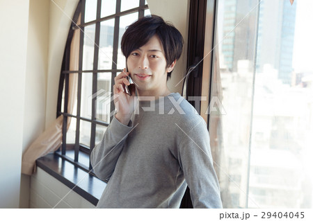窓際で電話している20代男性 窓際で電話している20代男性 29404045