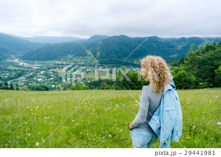 A young girl stands on top of a mountain in cloudy A young girl stands on top of a mountain in cloudy 29441981