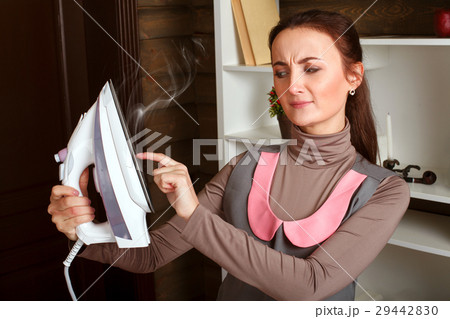 Woman in uniform touches iron hot soleplate 29442830