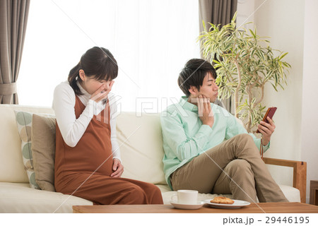 つわりの妊婦とスマホを見る夫 29446195