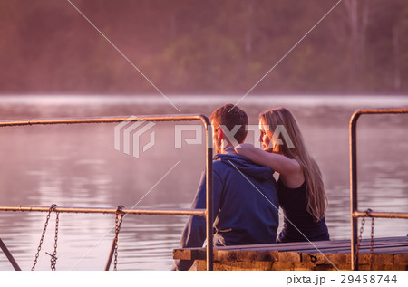 Romantic couple sitting on pier enjoying stunning Romantic couple sitting on pier enjoying stunning 29458744