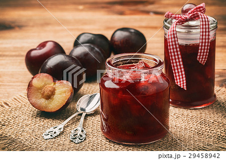 Plum jam in glass jars on wooden background. 29458942