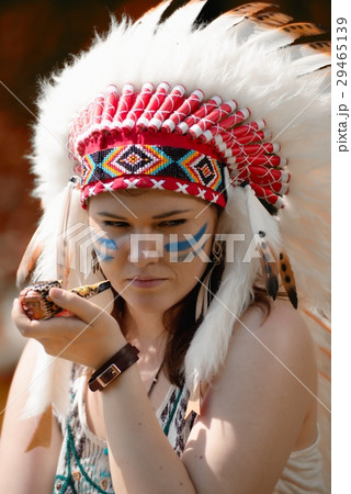Young woman in war bonnet headdress of American Indian smokes a pipe Young woman in war bonnet headdress of American Indian smokes a pipe 29465139