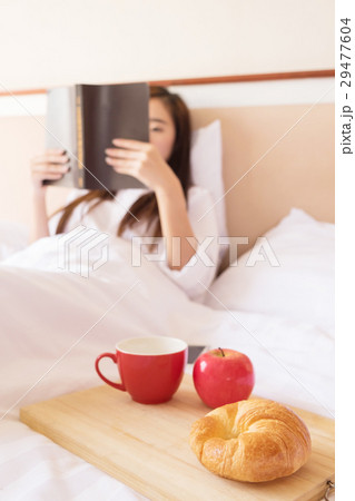 Woman reading book  and drinking coffee on bed during the mornin 29477604