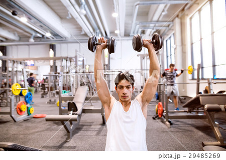Hispanic man in gym sitting on bench, working out Hispanic man in gym sitting on bench, working out 29485269
