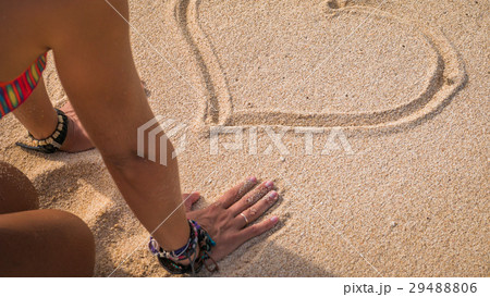 Young Woman Looking at Drawed Heart Shape in Sand 29488806