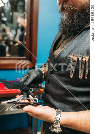 Bearded barber holding haircut tools free space 29489509