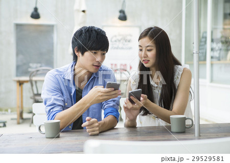 カフェでスマホを使う20代男女 29529581