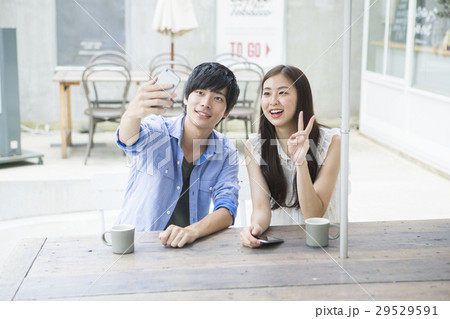 カフェでスマホを使う20代男女 29529591